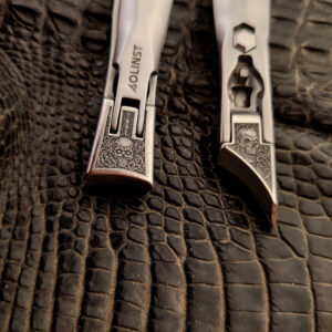 Engraved skull nail clipper with gothic metal design on black textured background