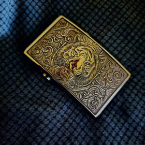 Engraved tiger belt buckle with ornate metal detailing on textured leather background